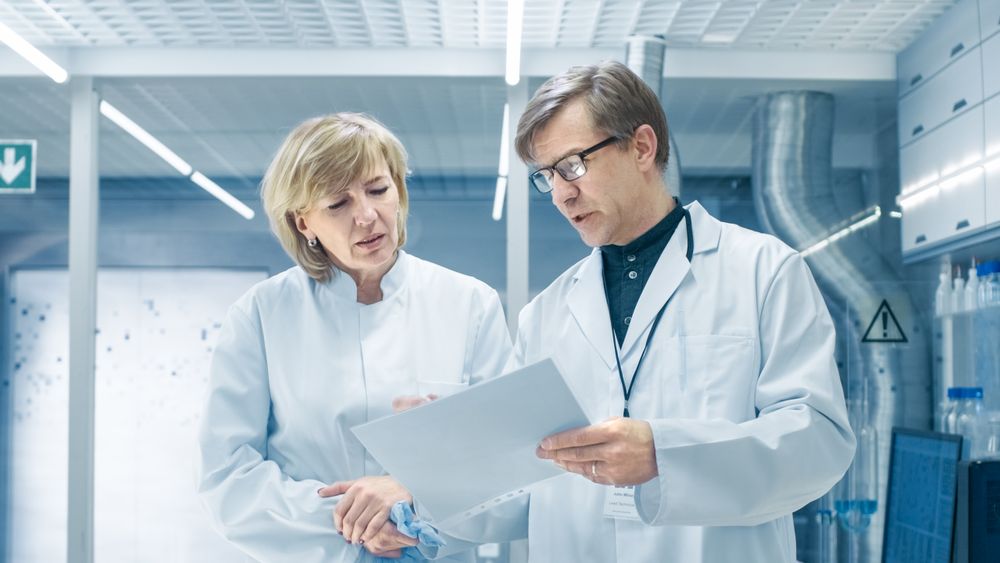 Female and Male Chief Scientists Walking Through Modern Laboratory and Discussing Future Possibilities.