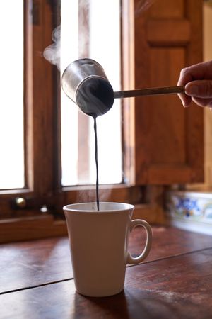 Unrecognizable person filling cup with hot coffee