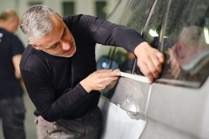 Mechanic putting protective tape on car