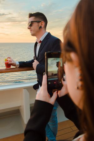 Woman taking photo of man on deck of ship at sea