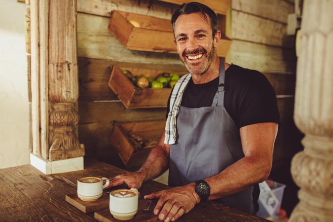 Portrait of a smiling male barista serving coffee