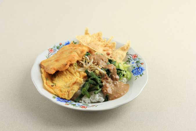 Plate of Indonesian meal with eggs and vegetables served with peanut sauce