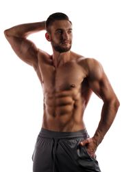 Bodybuilder competitor practicing front poses in bright studio