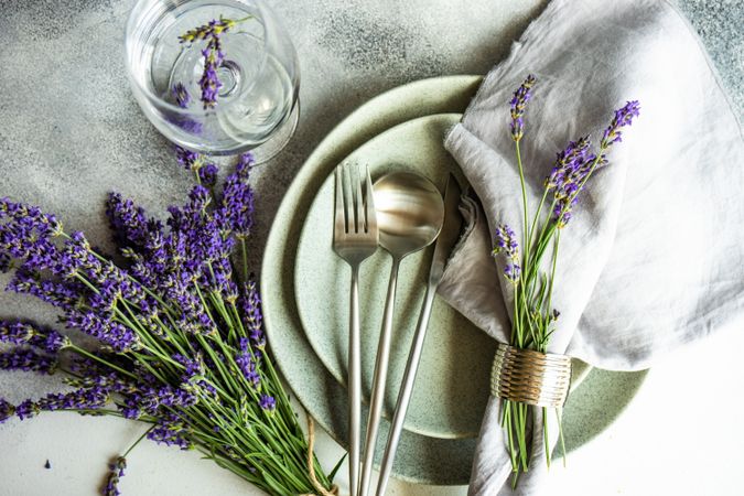 Delicate summer table setting with lavender flowers and glass of water and napkin