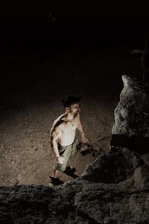 Man practicing rock climbing among large rocks in a forest