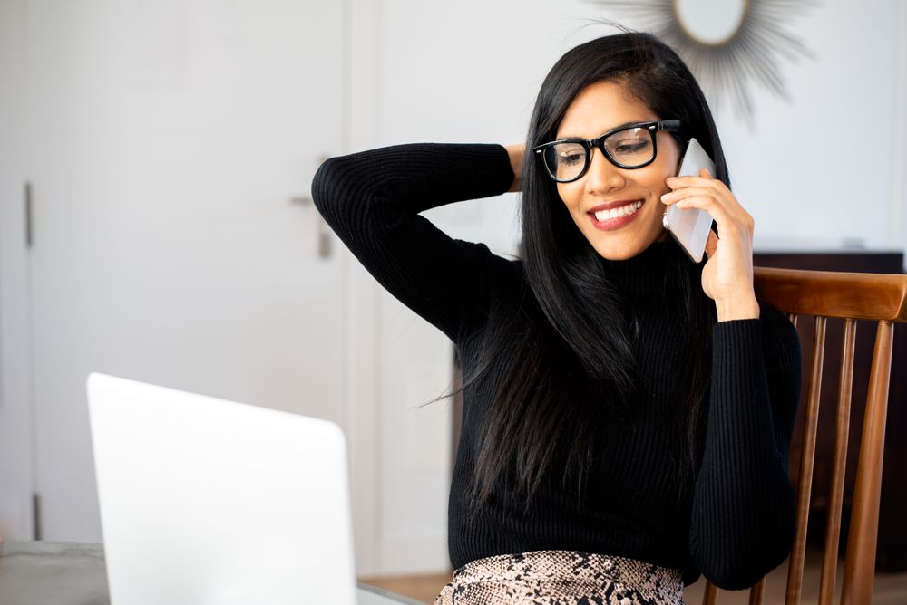 Businesswoman working from home on her computer and speaking on the mobile phone