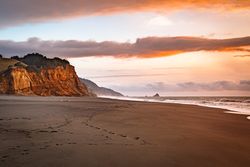 Footprints on a quiet beach with cliffs later afternoon