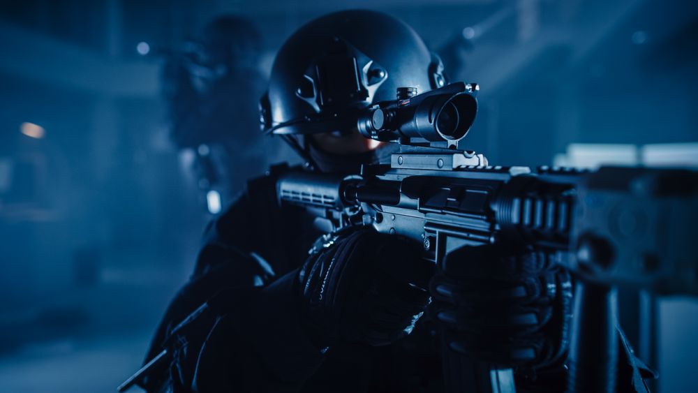 Close Up Portrait of Masked Squad Member of Armed SWAT Police Officers Who Storm a Dark Seized Office Building with Desks and Computers