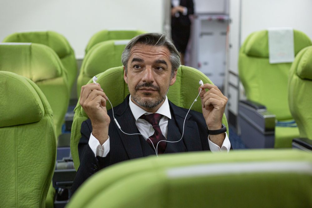 Male removing ear buds in flight