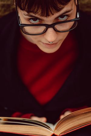 Young woman reading book on bench in park