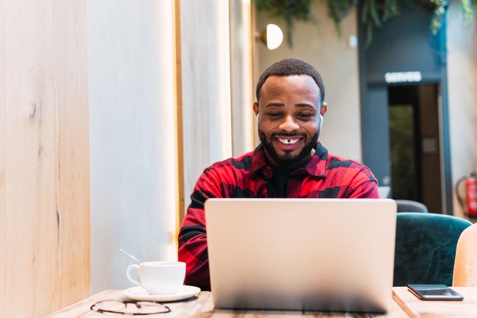 Smiling Black man working on laptop in cafe