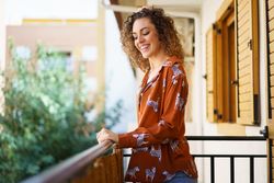 Cheerful young woman standing on balcony