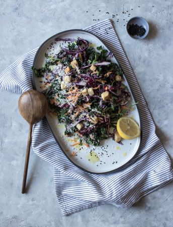Poppy seeds and lemon near vegetable salad with croutons and parmesan