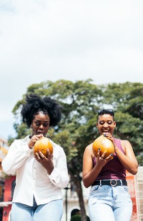 Latin American women having fun in the city drinking coconuts