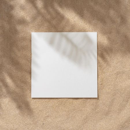 Sand with palm leaf shadows and central square