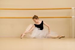 Ballet dancer elegantly poses on floor, showcasing artistry and poise