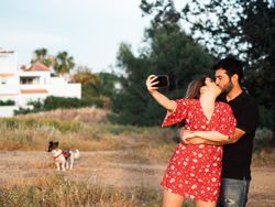 Couple kissing and taking photo outdoors