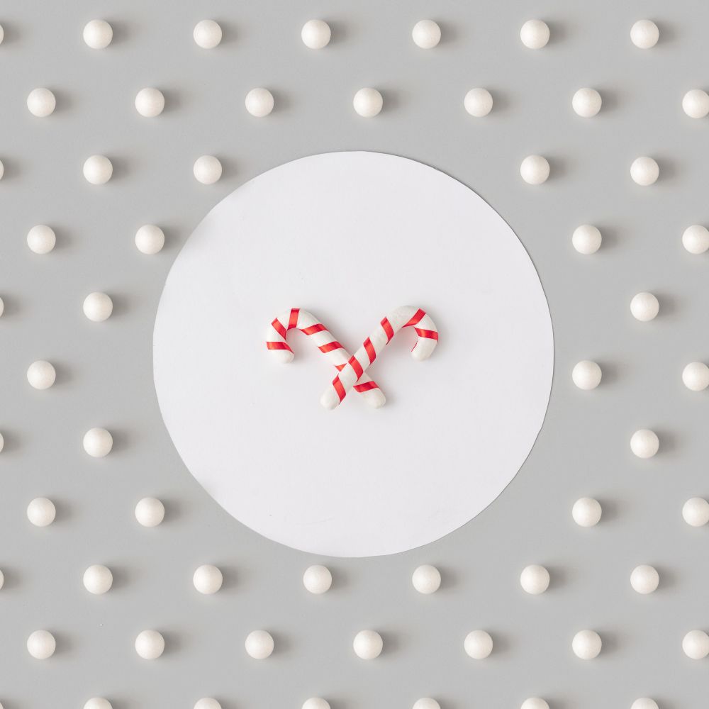 Holiday pattern with candy canes and snowballs on gray background