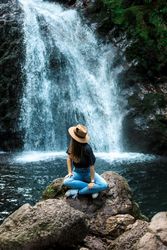 Smiling woman sitting near waterfall