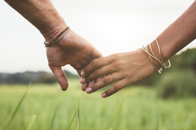 Close up of couple holding hands in the field