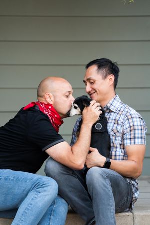 Close up portrait of smiling married couple sitting with their dog in front of their house
