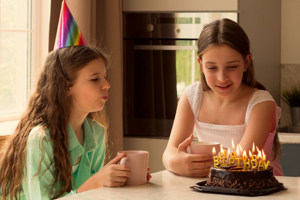 Close-up of girl blowing out candles on birthday cake.
