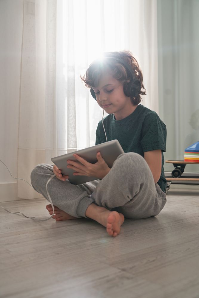 Focused preteen boy using tablet on floor in room