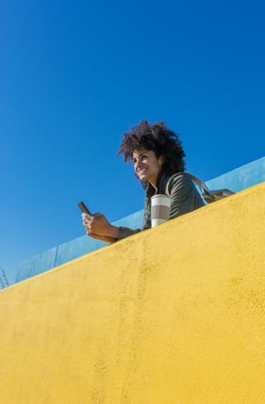 Black woman with afro hair leaning against brightly colored wall