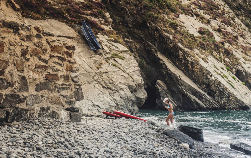 Woman with paddle board near cliff and sea
