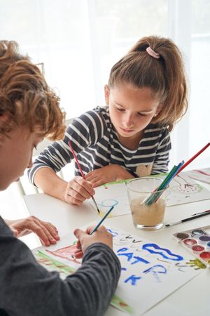Children painting together at table