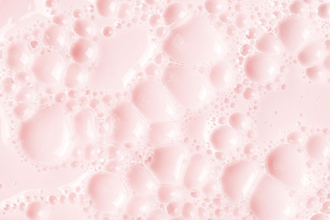 Light pink soap bubbles on liquid surface