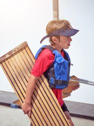 Boy with wooden board and blue life jacket