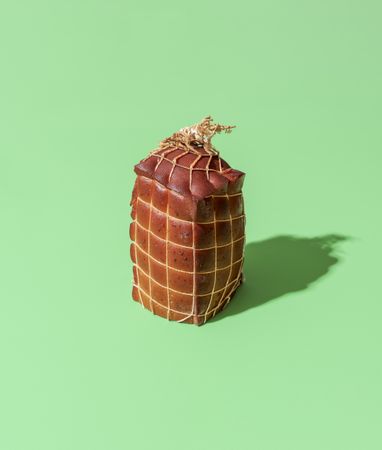 Smoked cheese, wrapped in strings, minimalist on a green background