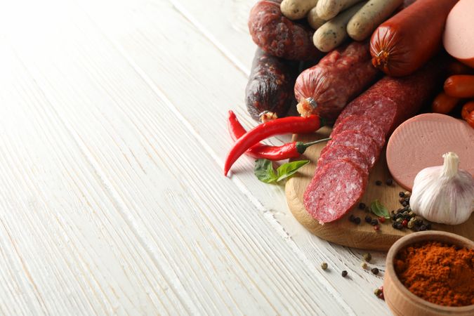 Variation of cured meats with peppers and spices on wooden background, copy space