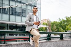 Man using smartphone leaning against wall