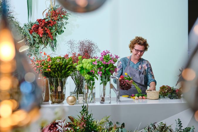 Cheerful woman arranging flowers on table