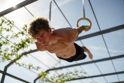 Strong young sportsman exercising with rings