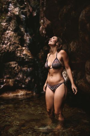 Adventurous woman standing in a plunge pool in a bikini