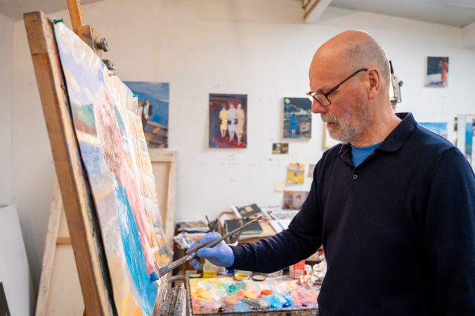 Older male artist painting in art studio