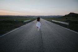 Anonymous woman running along countryside road
