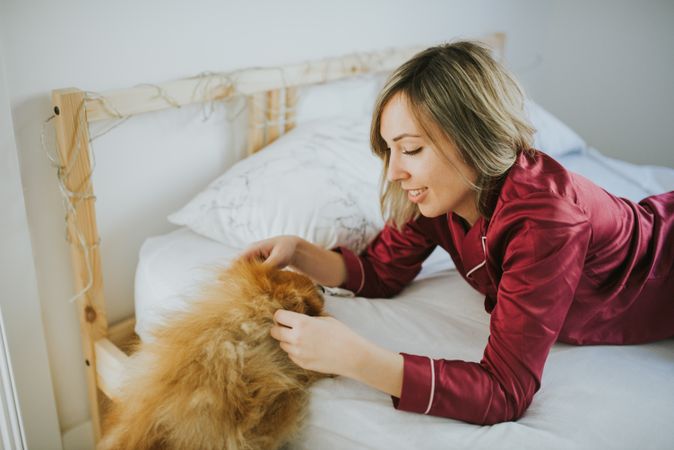 Smiling woman lying in bed with dog