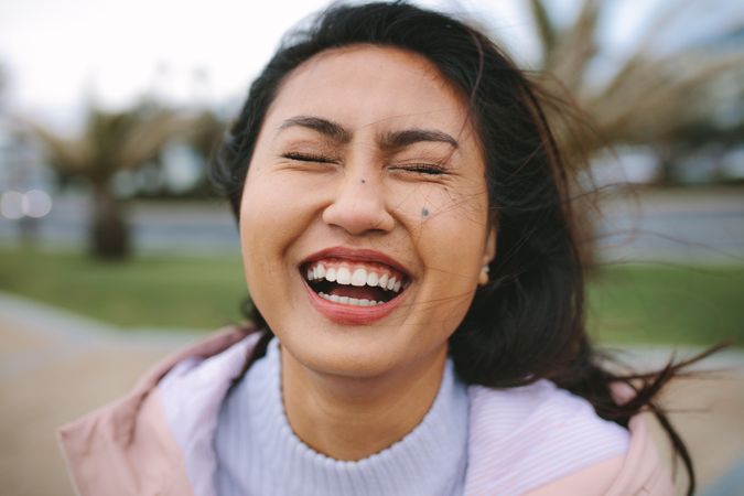 Close-up of young woman laughing with eyes closed