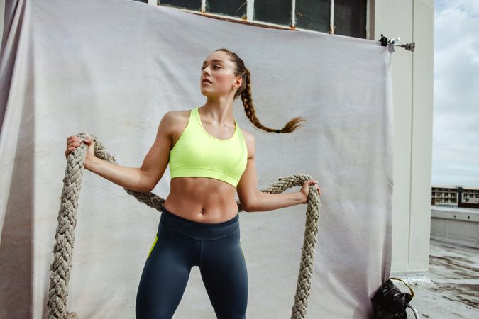 Fit woman doing cross training workout using battle rope