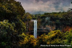 Waterfall surrounded by lush vegetation on cloudy day bx6kM5