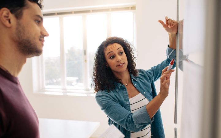 Female entrepreneur discussing business ideas and plans on a board in office