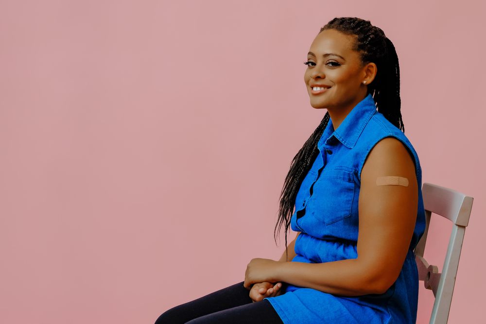 Smiling female with bandage after immunization in pink studio shoot, copy space