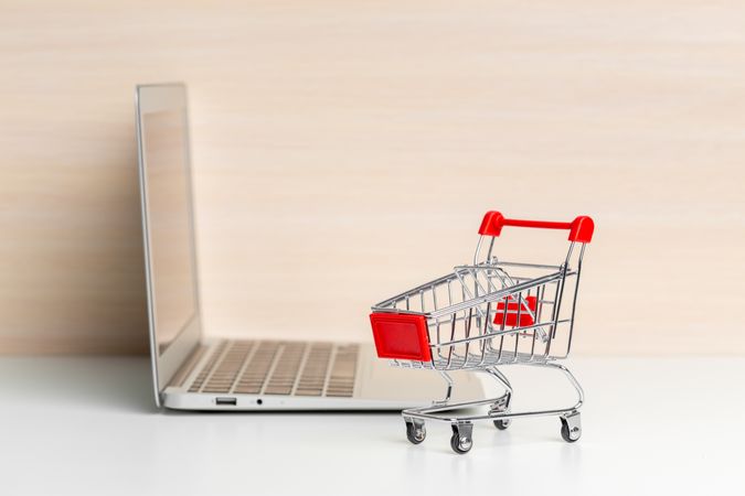 Miniature Shopping Cart Near Laptop Representing Online Shopping Concept