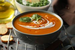 Two bowls of orange and green soup on wooden table