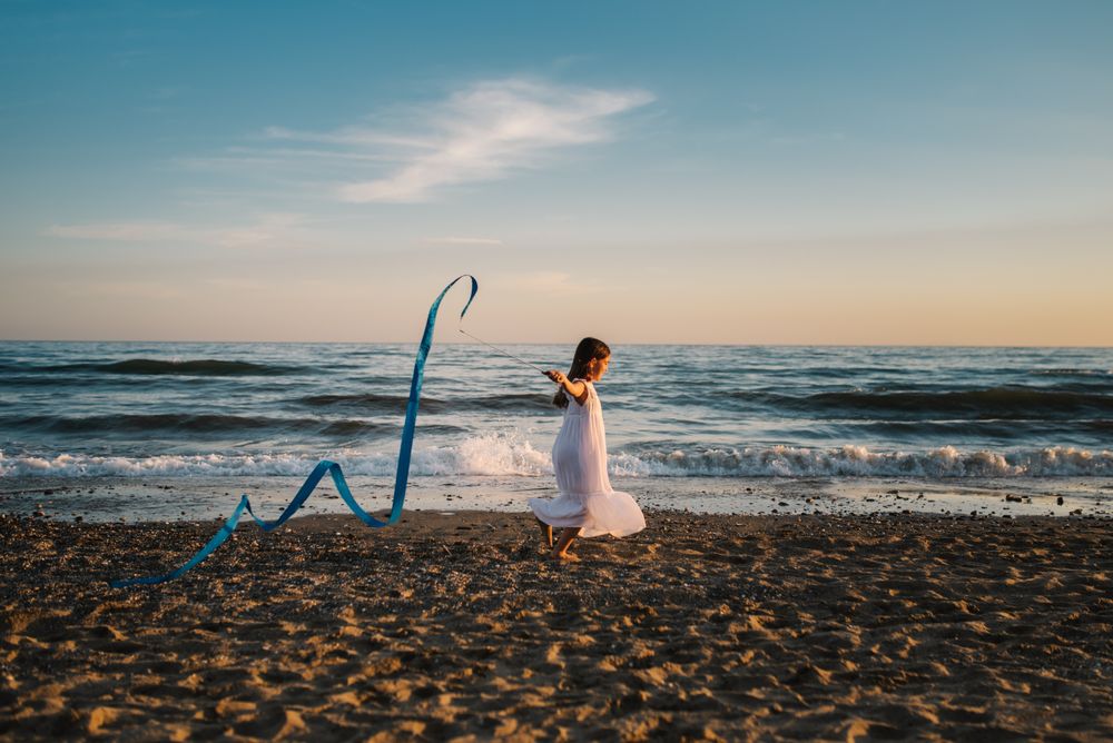 Adorable girl playing with ribbon on seaside