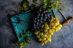 Top view of grapes on trey with wine opener and scissors